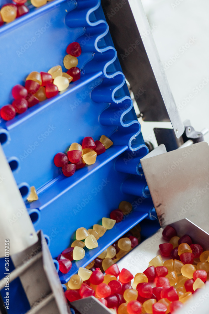 Closeup of an automatic conveyor producing orange jelly candies at the confectionary