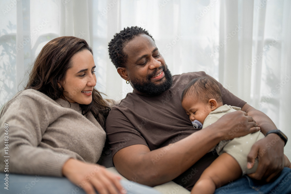 Obraz premium Happy family enjoying a quiet moment together while comforting their sleeping baby in a cozy living room