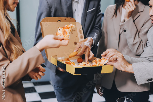 Asian office colleagues and friends enjoy a daytime BBQ with pizza and beer, celebrating Halloween and cheering for their favorite soccer team, creating a lively atmosphere filled with joy.