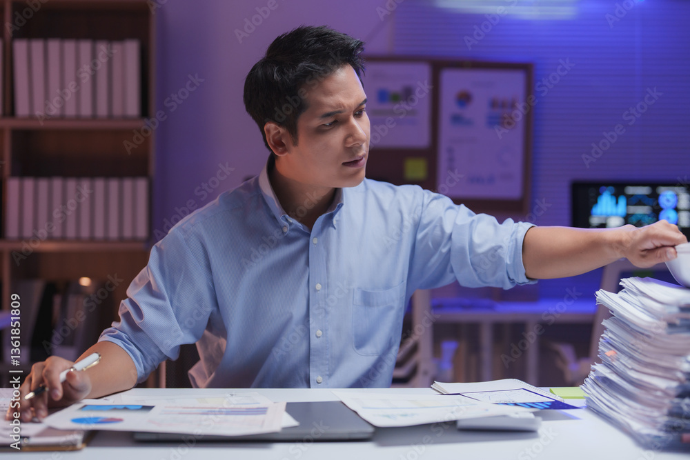 Young entrepreneur working late in a modern office, analyzing graphs and reviewing documents, immersed in financial reports while managing tight deadlines and stress Young entrepreneur working late in a modern office, analyzing graphs and reviewing documents, immersed in financial reports while managing tight deadlines and stress