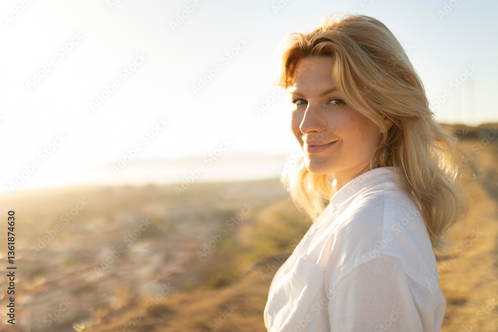 Blond woman enjoying golden hour light in scenic overlook Blond woman enjoying golden hour light in scenic overlook