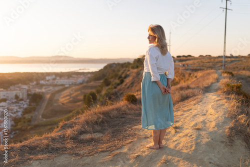 Obraz na plátne Woman admiring inspiring sunset view over city and sea from hilltop