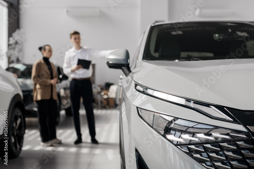 Fotografie A car dealer in a modern car dealership advises a customer on buying or leasing a new car