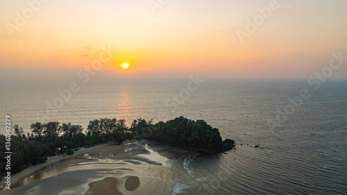 Photos A stunning aerial view of a peaceful coastal island at sunset, with golden hues reflecting on the calm ocean waters
