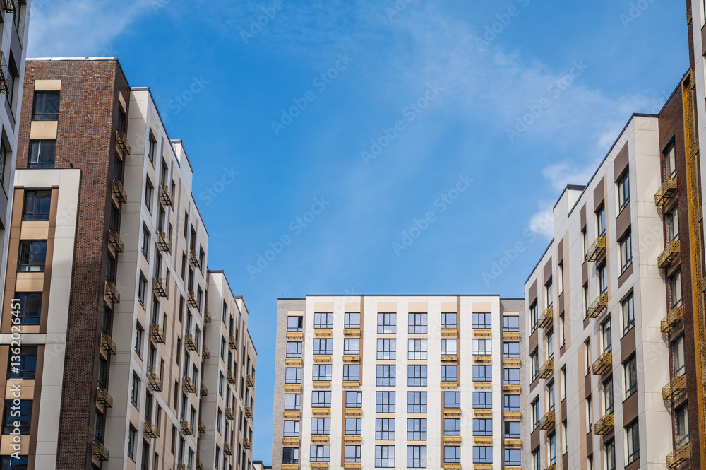 Fototapeta premium A low-angle shot of several modern apartment buildings on a sunny day under a blue sky.