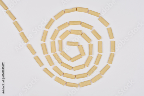 A row of small brown paper pieces is arranged in a spiral on a white background
