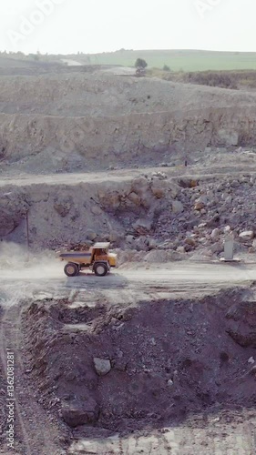 Vertical Format Video of Electric Truck loaded with ore is riding along the mine site. Industrial quarry, heavy industrial machinery working at the mining open pit