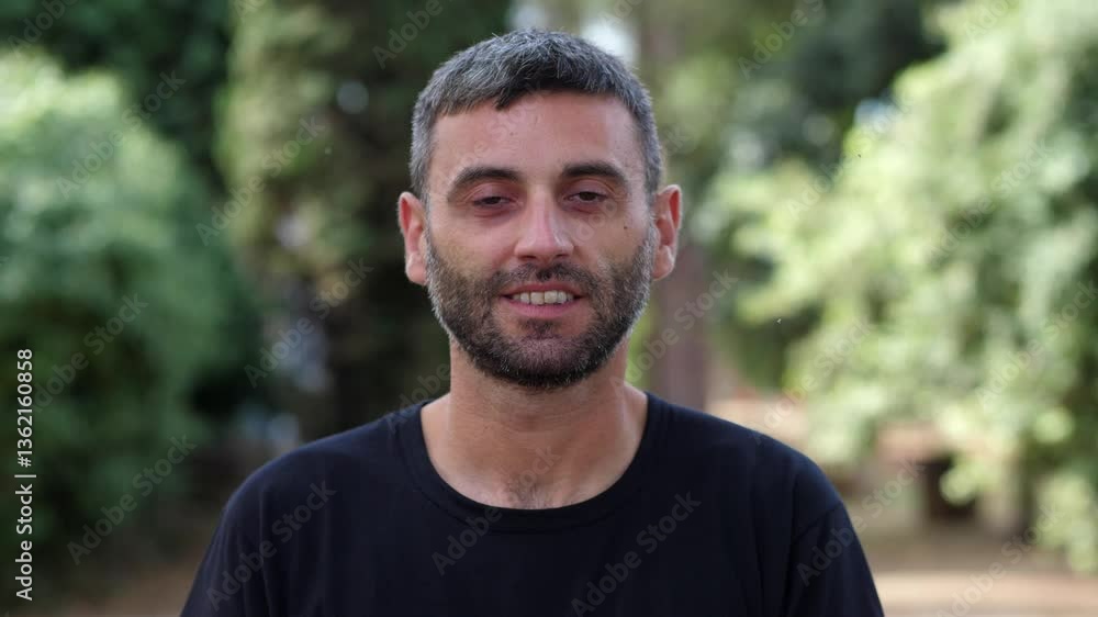 A young man in the park, transitioning from a serious expression to a smile, capturing a shift in mood from seriousness to happiness. A young man in the park, transitioning from a serious expression to a smile, capturing a shift in mood from seriousness to happiness.