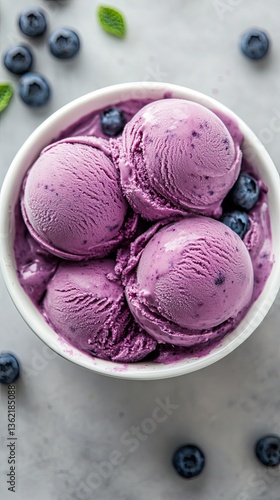 Delicious top view of scoops of blueberry ice cream with a swirl of whipped cream in a bowl, flatlay photography, product recipe food photography, solid light gray background