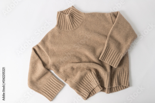 Soft sweater of light brown beige luxury natural cashmere wool lying on white background. Autumn and winter pure wool warm clothing.