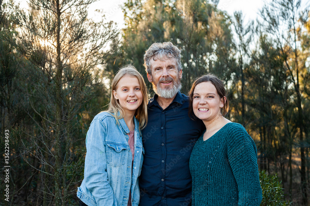 Father standing with happy daughters outside in bushland Father standing with happy daughters outside in bushland