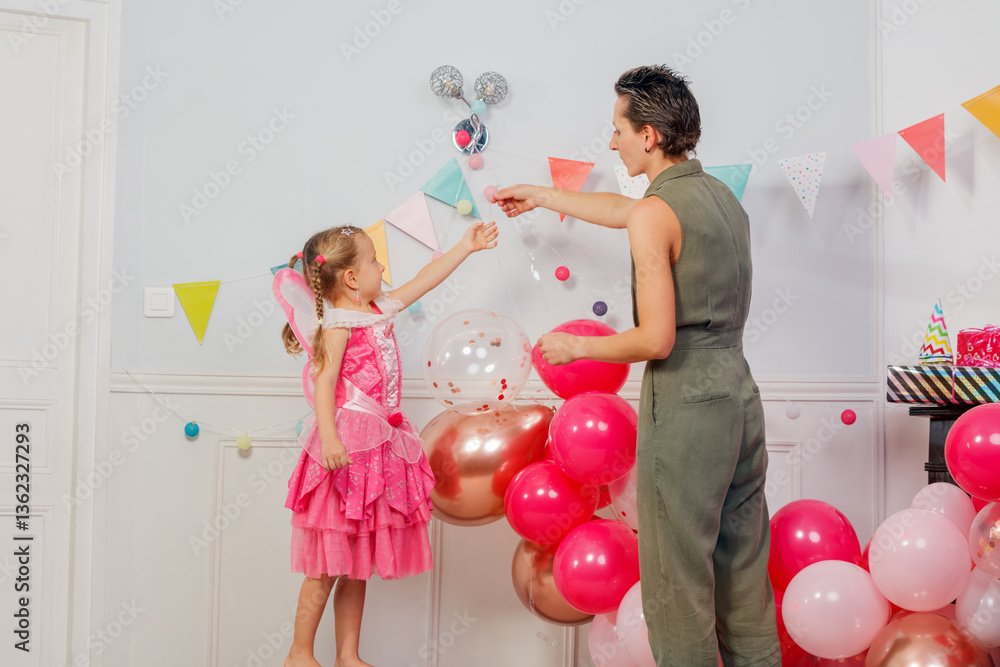 Mother with daughter decorate room for children birthday party