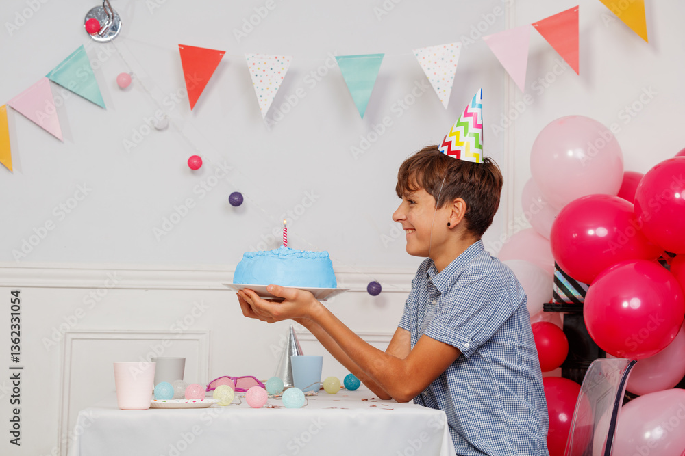 Cheerful boy teen at birthday party celebrate with blue cake