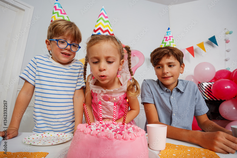 Cute girl with brothers blowing out candles on her bday cake