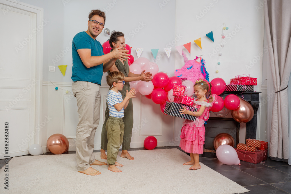 A girl in pink collects presents as happy family applauds her