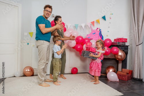 Obraz na płótnie A girl in pink collects presents as happy family applauds her w salonie