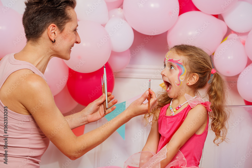 Child gets face painted with rainbow colors during a celebration