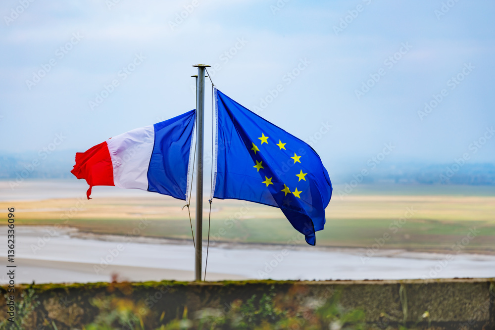 Flags of France and EU wave against misty autumn shore, Normandy