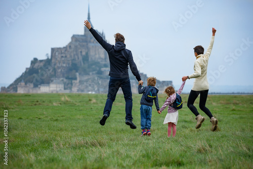 Cheerful family jump near a castle, embracing adventure, France