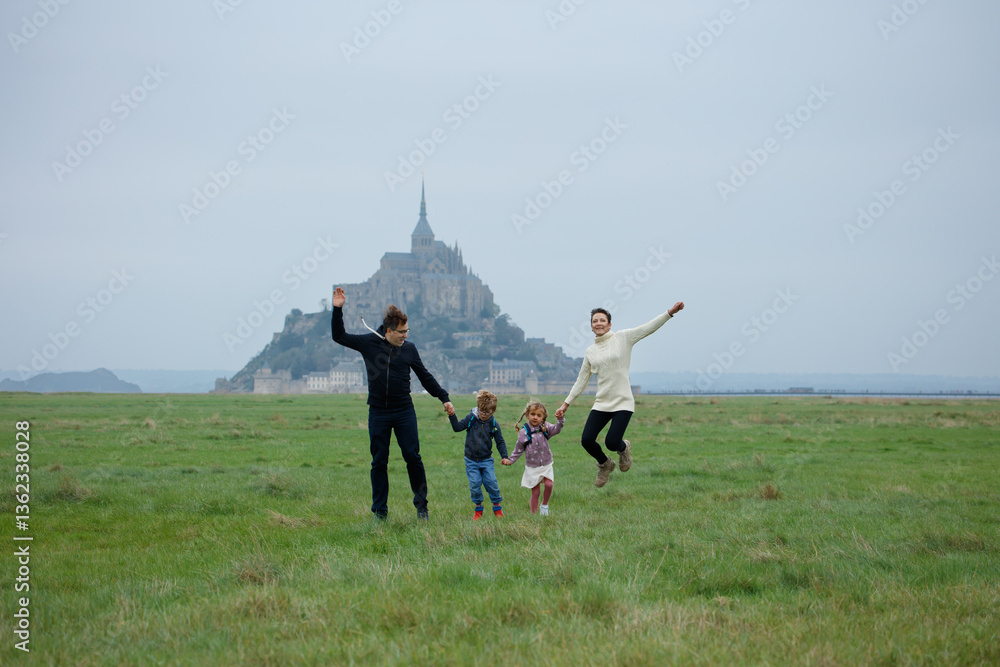 Happy family jumping in front of Mont Saint-Michel on cloudy day