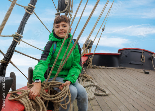 Obraz na płótnie Smiling kid tourist in green explores a old pirate ship deck w salonie