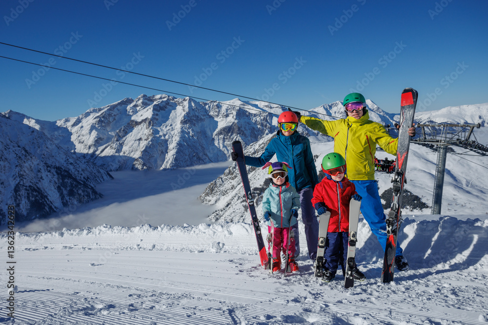 A family with kids poses happily on snowy slopes in ski gear