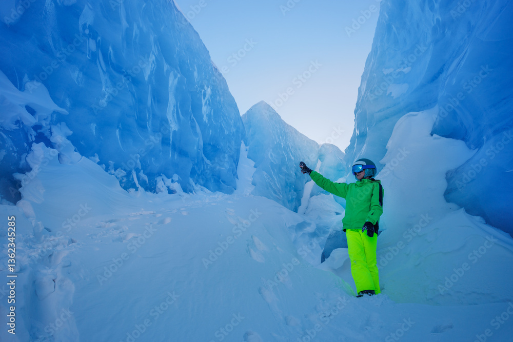 Brightly dressed skier poses in a beautiful ice-filled crevice