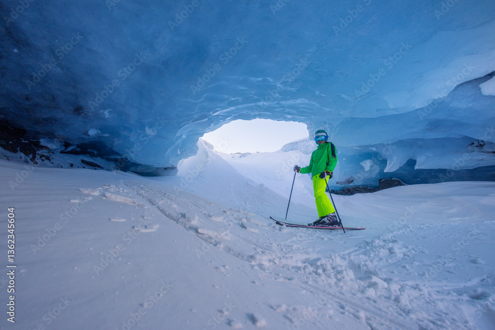 Skier teenager explores stunning blue ice cave in bright outfit