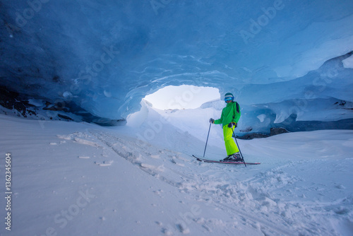 Obraz na płótnie Skier teenager explores stunning blue ice cave in bright outfit w salonie