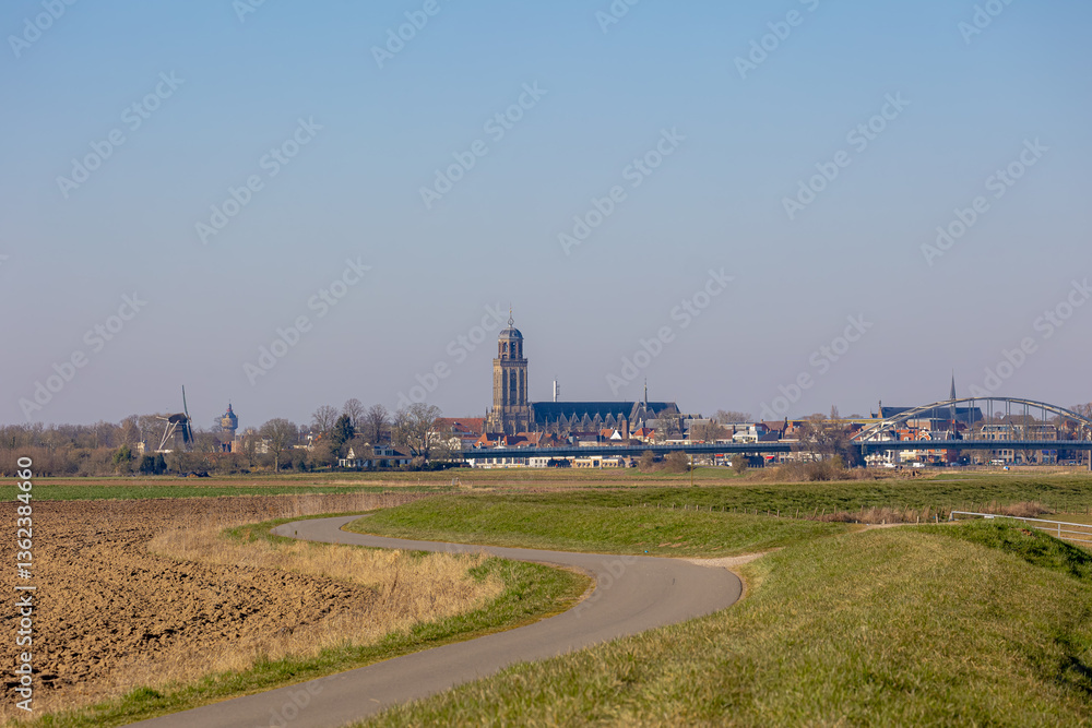 Countryside road in suburb of Deventer, Early spring landscape with farmland and green grass field, A city and municipality in the Salland historical region of the province of Overijssel, Netherlands. Countryside road in suburb of Deventer, Early spring landscape with farmland and green grass field, A city and municipality in the Salland historical region of the province of Overijssel, Netherlands.