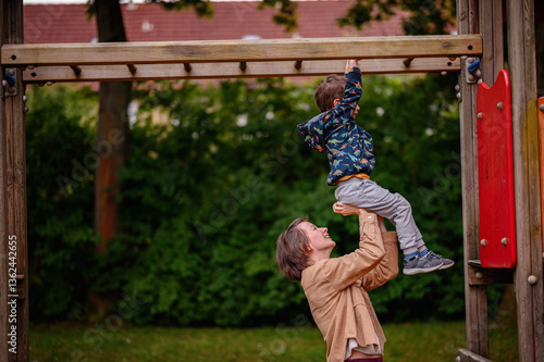 Smiling Parent Assists Child on Monkey Bars at Playground