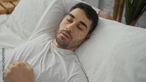 Handsome man sleeping peacefully on a comfy bed in a cozy bedroom setting inside a home, exuding a sense of relaxation and comfort in the indoor environment.