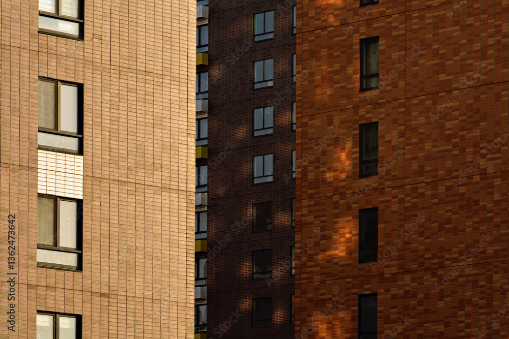 Fototapeta premium Warm-toned building facades with repetitive windows and soft shadows create a calm urban background with structured vertical geometry.