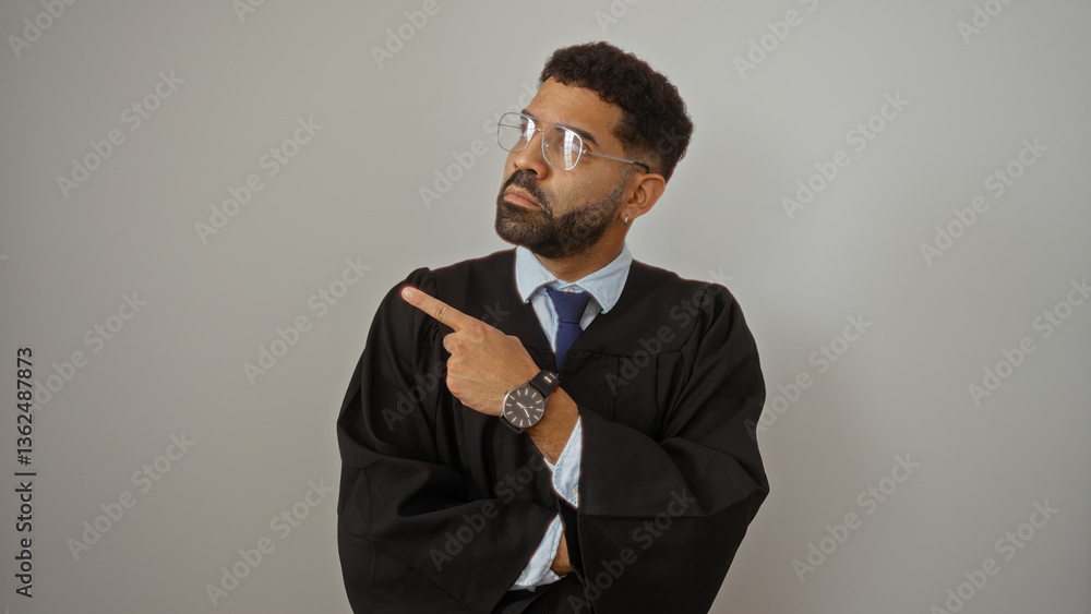 Confident young man wearing black gown and glasses pointing to the side against isolated white background Confident young man wearing black gown and glasses pointing to the side against isolated white background
