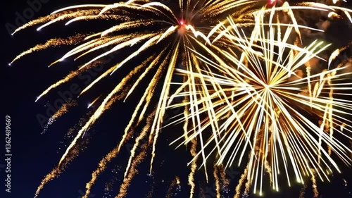 Bright golden fireworks illuminate the night sky, creating a breathtaking spectacle. Sparks and smoke trails fill the space, forming a mesmerizing pattern of light and movement.