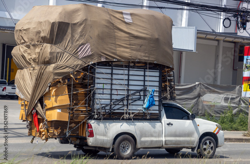 Obraz na płótnie A pick-up truck fully loaded with paper for recycling drives down a city street, Thailand w salonie