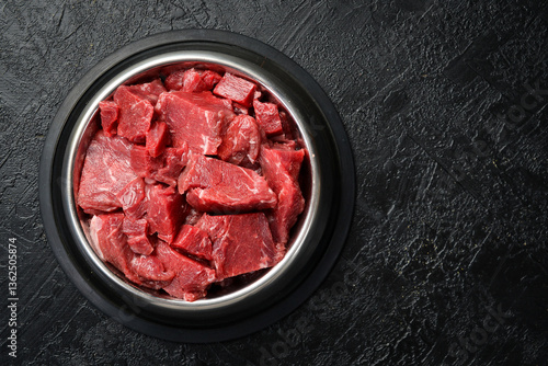 Canvastavla Bowl for a pet with fresh meat. On a black stone background.