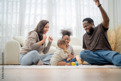 Joyful family playing together indoors while building with colorful blocks in a bright living room