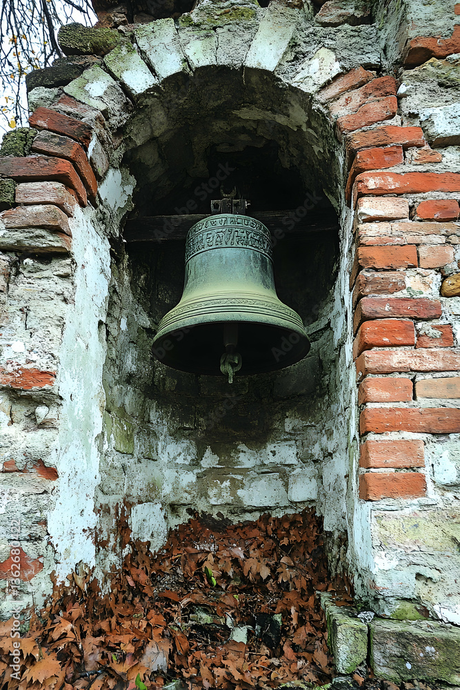 Obraz premium Old bell in weathered brick niche, fallen leaves below