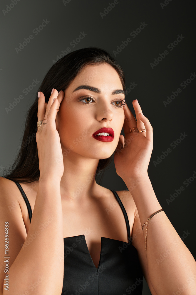 Fototapeta premium A young woman with red lips and brown hair against a grey backdrop