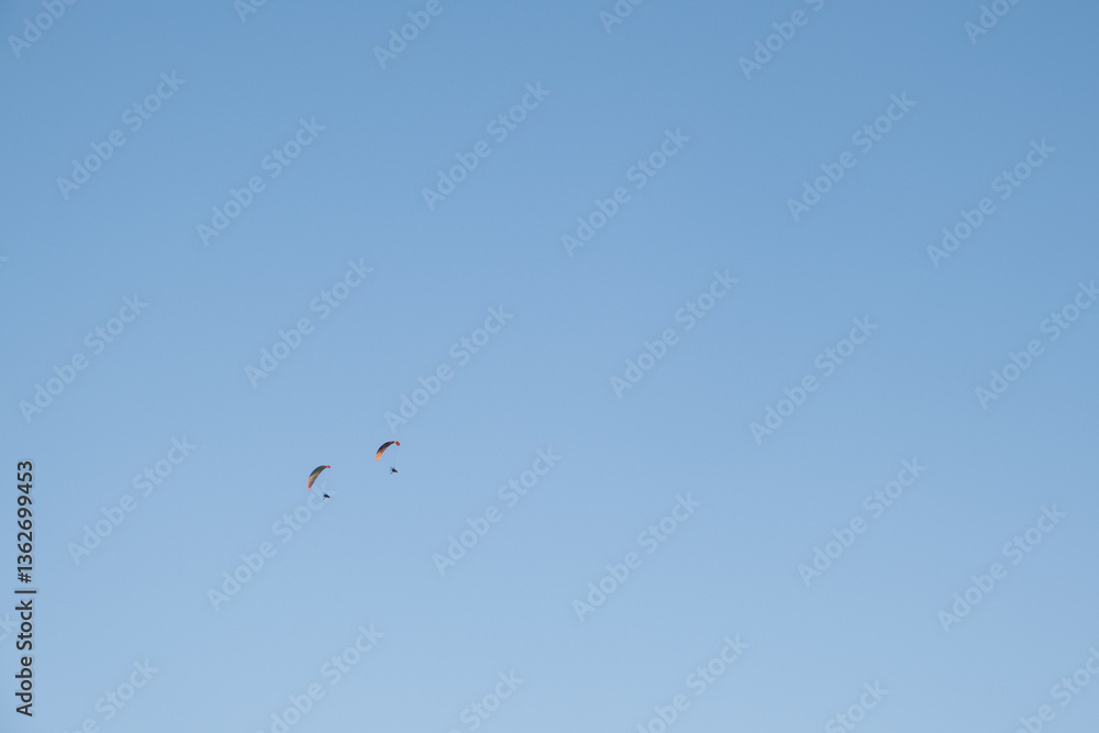 Two small paraglidings fly quietly on a volcanic mountain range at sunset. The sky is blue brilliant and clear on a summer day on the southern coast of Spain. Relax and Flight Two small paraglidings fly quietly on a volcanic mountain range at sunset. The sky is blue brilliant and clear on a summer day on the southern coast of Spain. Relax and Flight