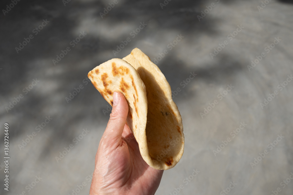 Authentic Sri Lankan Pol Coconut Roti in hand. Traditional recipe flat bread with red onion and chilli. Copy space. Close up.