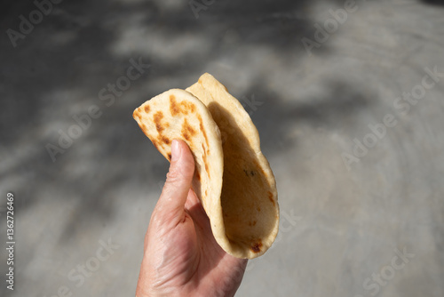 Authentic Sri Lankan Pol Coconut Roti in hand. Traditional recipe flat bread with red onion and chilli. Copy space. Close up.