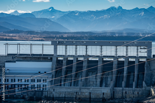 Hydro dam with power station overlooking distant Canadian Rockies near Cochrane Alberta Canada.
