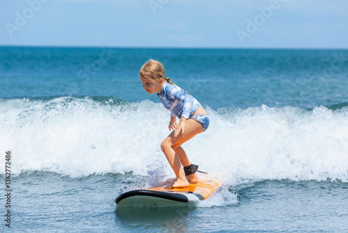 Canvas Print Happy baby girl - young surfer ride on surfboard with fun on sea waves