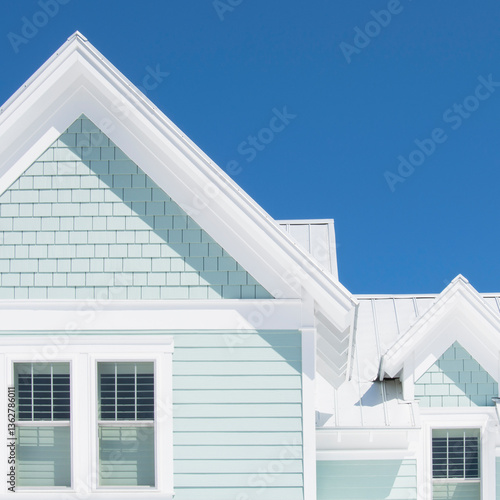 Exterior of white coastal cottage against clear blue sky