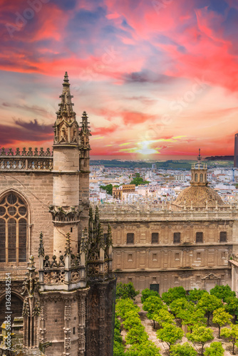 Seville Cathedral and orange tree courtyard at sunset with dramatic pink sky over the historic old town of Seville, Spain