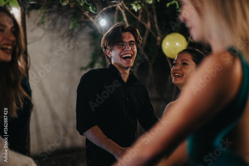 Fotografie A lively moment of friends enjoying laughter and togetherness outdoors under the ambient lights
