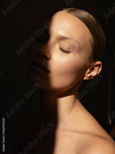 Fényképezés Close-up portrait of a naturally beautiful face in warm golden sunlight, with soft shadows adding depth