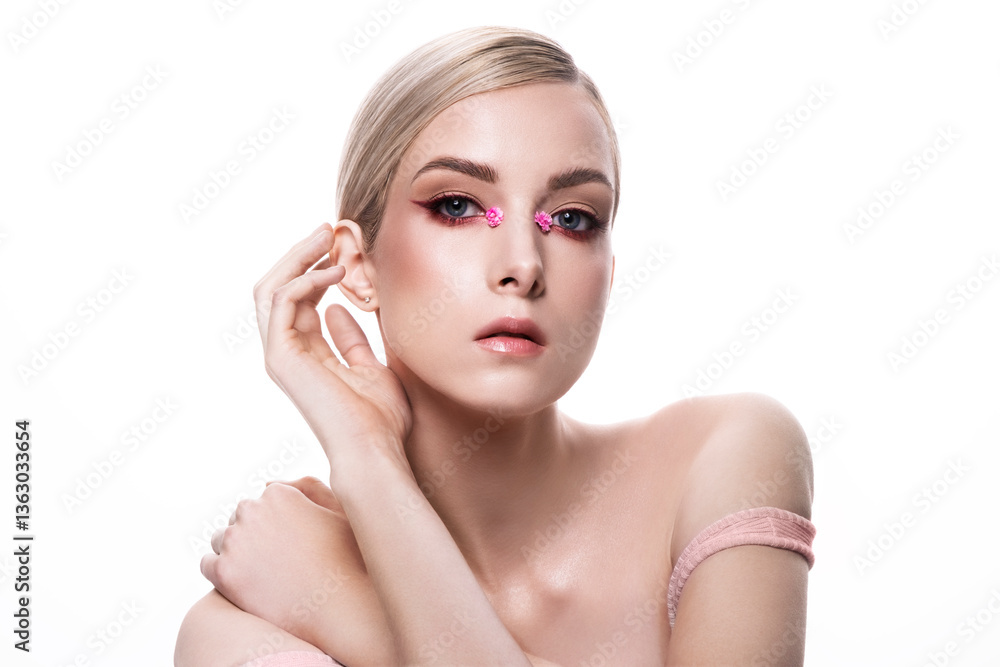 A womans face closeup with pink flowers delicately on her eyes A womans face closeup with pink flowers delicately on her eyes